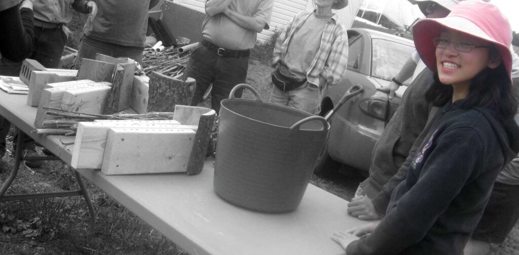 A gardener standing in front of a table and smiling.